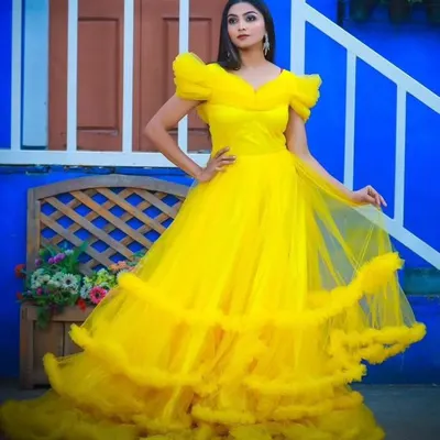 Make a grand entrance with this stunning yellow ball gown, available for rent. The ruffled sleeves and voluminous tiered skirt create a dramatic and unforgettable look.