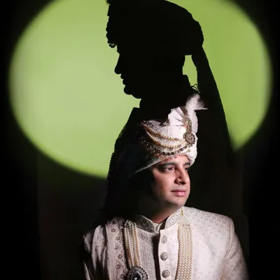 An artistic portrait of the groom with a creative shadow effect, highlighting his traditional sherwani and turban.