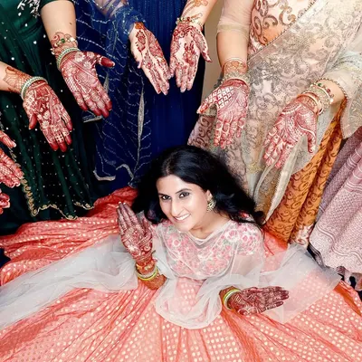 A beautiful and creative Mehndi photo, with the bride surrounded by the henna-adorned hands of her loved ones. This shot symbolizes blessings and togetherness.