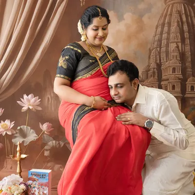 A beautiful couple's portrait in a traditional setting, where the father-to-be listens lovingly to the baby bump. This captures a classic moment of anticipation in a South Indian maternity shoot.
