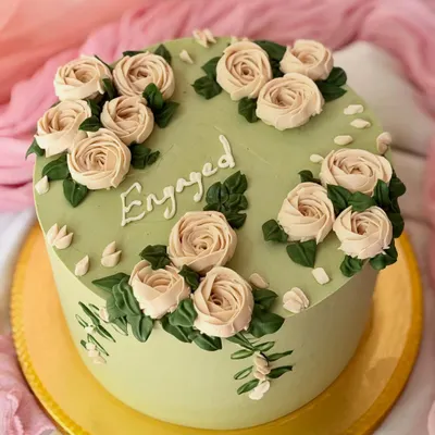 An elegant engagement cake in a beautiful sage green. The cake is adorned with hand-piped buttercream roses in a soft beige, creating a sophisticated and romantic look.