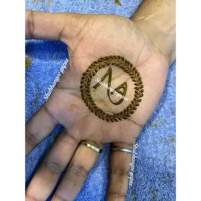 A simple and classic groom's mehndi. This design features the couple's initials inside a leafy wreath, a popular and personal choice for grooms.