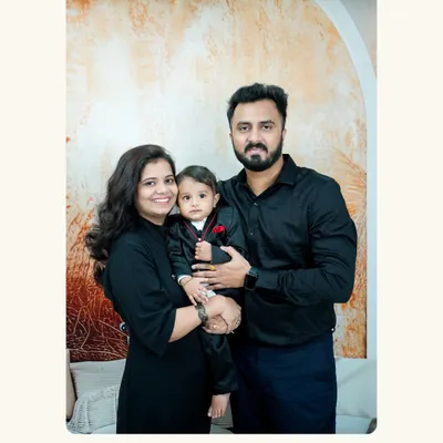 A classic family portrait. The parents and their little one, dressed in matching black outfits, create a timeless and elegant image.