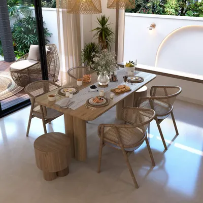 This dining space embodies a natural, bohemian aesthetic that connects directly with the outdoors. We used earthy materials like wood and rattan for the furniture and kept the color palette neutral to complement the view of the green patio just outside the sliding glass doors.