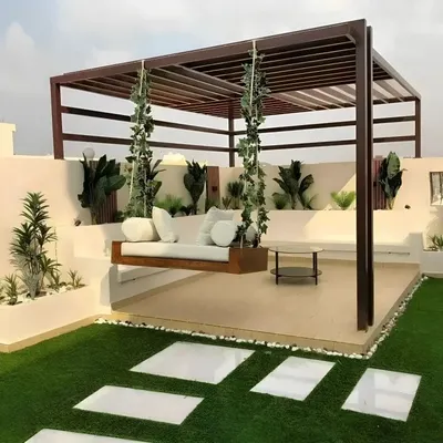 This rooftop terrace design combines natural and modern elements to create a serene escape. I used a dark wood pergola to frame the space, adding a custom-built hanging sofa for ultimate relaxation. The design is completed with artificial turf, white stone pavers for a clean walkway, and built-in planters with lush greenery.