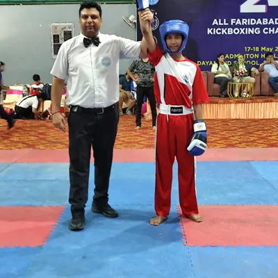 A young champion's hand is raised by the referee after a victorious bout at the 24th Faridabad District Kickboxing Championship. This moment captures the essence of hard work paying off.
