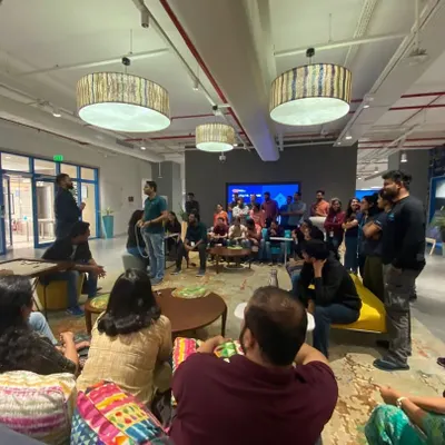 Leading an informal team-building session in a relaxed office lounge area. These workshops are designed to be casual and interactive, encouraging open participation and connection among colleagues.