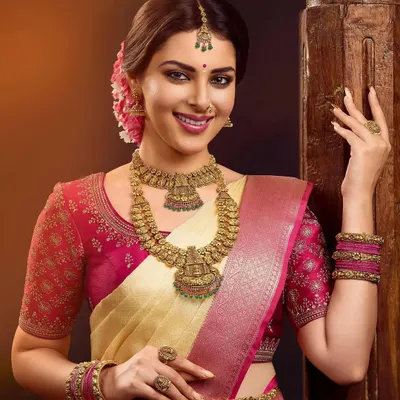 A stunning South Indian bridal look created for a PNG Jewellers campaign. The model wears a cream and pink Kanjivaram saree, styled with heavy, intricate temple jewelry, including layered necklaces and a maang tikka.