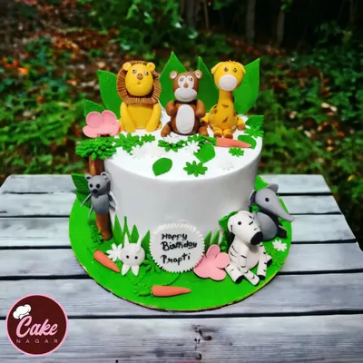 A delightful jungle theme cake set against a natural backdrop. This cake features a whole crew of cute, handcrafted fondant animals including a lion, monkey, giraffe, and zebra.