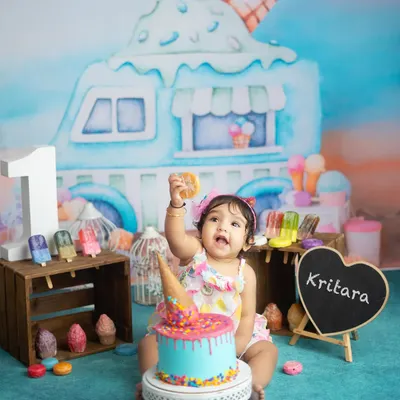 One is sweet. This little girl is celebrating her first birthday with an ice cream themed cake smash. The colorful cake and props create a fun and festive scene.