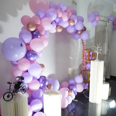 This is a close-up of an indoor home decoration I did for a client. The circular balloon arch in pink, purple, and rose gold is complemented by lit pedestals and small decorative props.