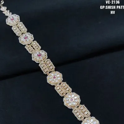 A close-up of a premium quality Kundan sheesh patti with a floral design and red stone center. This hair accessory adds a royal touch to any bridal look.