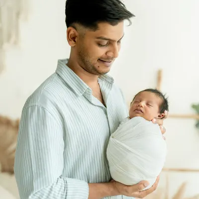 A father's world held gently in his arms. This portrait captures the quiet awe and tenderness of a new dad holding his sleeping newborn.