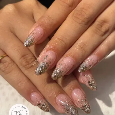 A full-on glamour set with a silver and gold glitter fade. These long, almond-shaped nails feature a nude base that transitions into a dense, sparkling glitter tip.