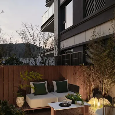 This render shows a cozy and private outdoor seating area on a wooden deck. The design incorporates comfortable seating, soft up-lighting on bamboo plants, and a wooden fence to create a serene urban sanctuary.