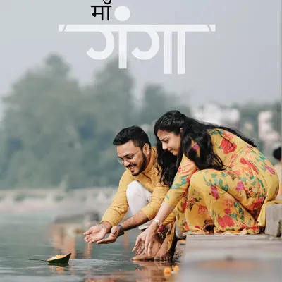 A beautiful, serene shot of a couple in matching yellow ethnic wear offering a diya to the Ganga river, capturing a moment of spiritual connection.