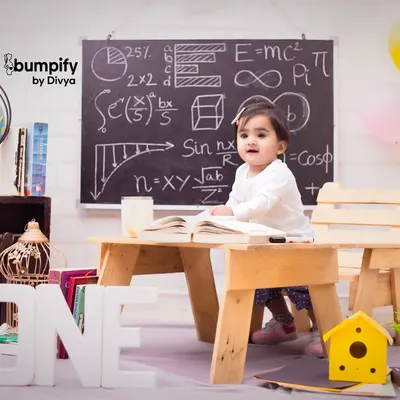 Celebrating a first birthday with a "little scholar" theme! This setup includes a tiny desk, a chalkboard of equations, and books to create a fun, smart setting.