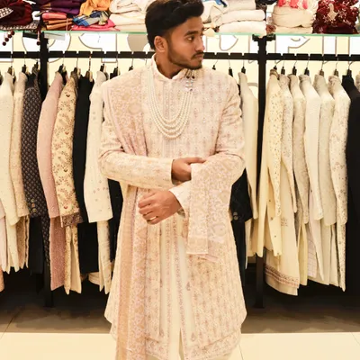 This is a full look at one of my popular groom's sherwanis. The light-colored fabric has subtle all-over embroidery, paired with a matching stole and a multi-layered pearl necklace for a truly regal appearance.