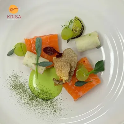 A deconstructed plate featuring cured salmon, fried oyster mushrooms, and grapes with a vibrant green puree. This dish is an example of our modern culinary style, focusing on artistic plating and complex flavor pairings.