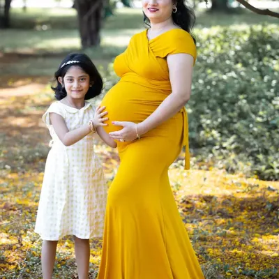 A sweet moment between a mother and her daughter. The older sister-to-be gently holds her mom's baby bump, excited to meet her new sibling.