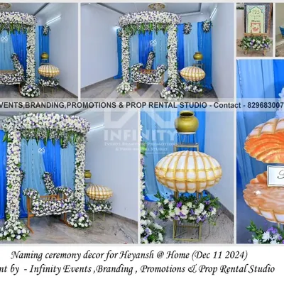 A beautiful naming ceremony decor at home, blending traditional and modern elements. The setup features a floral-decorated swing and a unique seashell prop for the name reveal, against a blue and white draped backdrop.