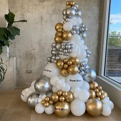For a modern take on Christmas, I can build a custom balloon Christmas tree like this one. This installation uses a mix of white, chrome silver, and gold balloons in various sizes to create a stylish, festive structure that's perfect for corporate lobbies or contemporary homes.