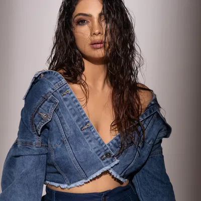 A raw and intense portrait. The off-shoulder styling of the denim jacket and the messy, wet hair create a bold and unapologetic fashion look.