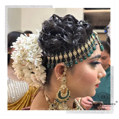 A beautiful and intricate bridal updo. This hairstyle features a classic bun adorned with a large gajra and a traditional matha patti.