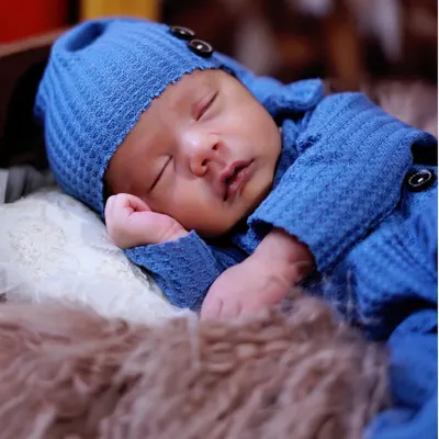 A close-up of a peacefully sleeping newborn in a cozy blue knit outfit. I focus on capturing the tiny details, like their soft cheeks and gentle breaths, that you'll want to remember forever.