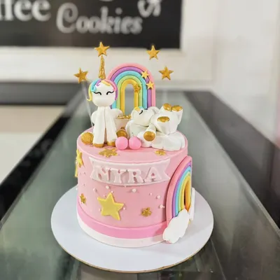A magical unicorn and rainbow cake. This pink cake is adorned with a fondant unicorn, rainbows, stars, and a sleeping bear on a cloud.