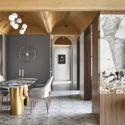The vaulted ceiling is the defining feature of this apartment, creating a sense of grandeur and warmth. This view shows how it connects the dining area with the rest of the home, complemented by geometric floor tiles and a bespoke marble dining table.