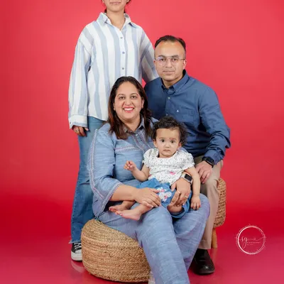 A classic family portrait against a vibrant red backdrop. I work to make everyone feel relaxed, resulting in genuine smiles and a beautiful photo that captures this moment in your family's life.