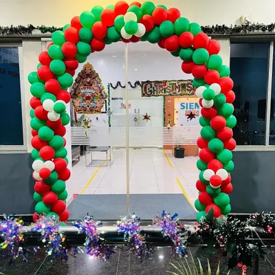 A large Christmas balloon arch in festive red, green, and white, designed for an office entrance. The base is decorated with shiny tinsel, creating an impressive and welcoming holiday display for a corporate environment.