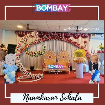 A grand stage setup for a Naamkaran Sohala. This features throne-like chairs for the parents, a floral arch, and our popular shell prop for the name reveal.