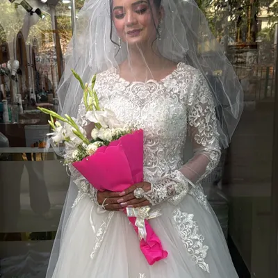 A beautiful bride in our classic long-sleeved Christian wedding gown. The intricate lace detailing on the sleeves and bodice, paired with a simple veil, creates a look of timeless elegance.