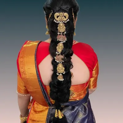 An intricate bridal braid featuring traditional temple jewelry pieces set along its length. This hairstyle is a statement of heritage and is designed to be the crowning glory of a South Indian bridal ensemble.