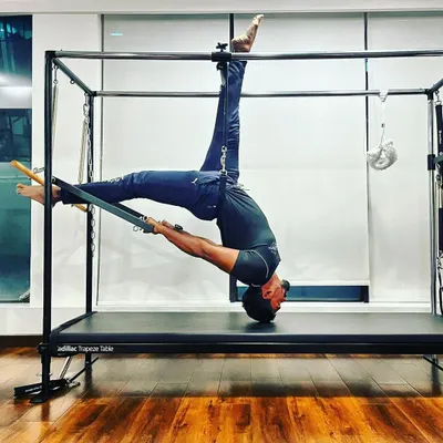 An unbending tree is easily broken. This advanced inverted stretch on the Cadillac Trapeze Table is a testament to the power of flexibility. This pose helps decompress the spine and requires significant core control and strength.