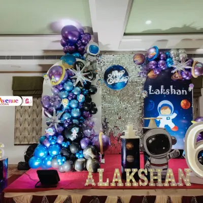 A complete outer space themed birthday party for Lakshan. This grand setup includes a shimmering silver backdrop, a galaxy balloon garland, astronaut cutouts, and a large light-up number '6'.
