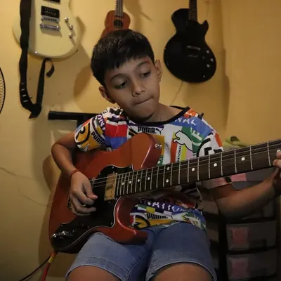 The focus in his eyes says it all. Here, we help students channel their passion into every note, learning the art of electric guitar with dedication.