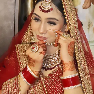 A classic bridal pose, adjusting the nose ring. This look features a sharp cut-crease eye makeup style and a matte red lip, techniques we practice extensively in my professional makeup course.