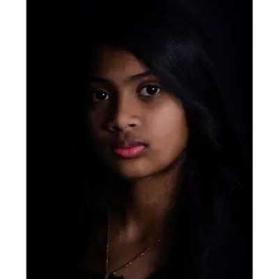A dramatic, low-key portrait of a young woman. This style of lighting creates a moody and artistic feel, highlighting facial features in a subtle way.