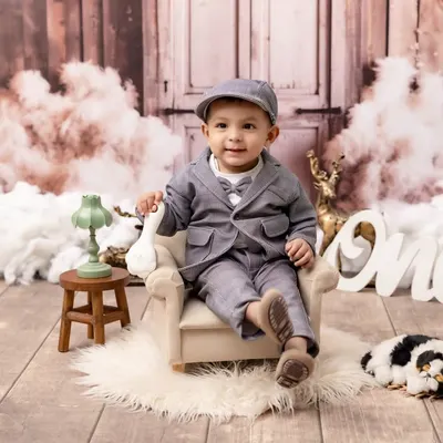 Celebrating one year of life with style and personality. This little gentleman is dressed in a dapper suit for his first birthday photoshoot, set against a classic, rustic backdrop that makes his big milestone feel even more special.