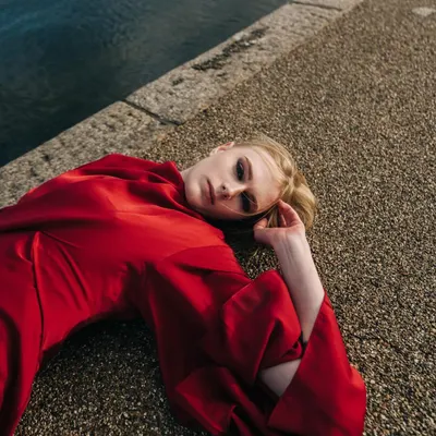 An overhead shot from my first editorial in London. The model lies on the concrete embankment, with the rich red dress creating a striking contrast against the cool tones of the water and stone.