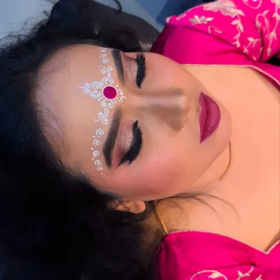 A close up of the traditional Bengali bridal eye makeup and chandan art. The white and red design on the forehead is a beautiful cultural element.