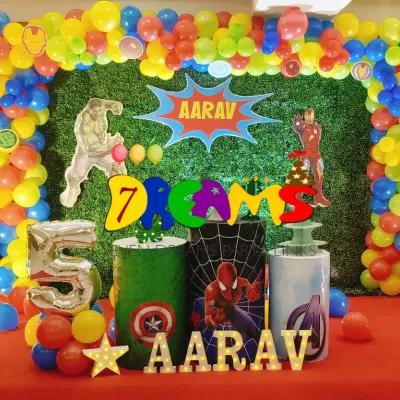 An Avengers-themed party with a green grass backdrop. This decoration includes a vibrant balloon frame and cutouts of Hulk, Captain America, and Iron Man for an action-packed celebration.