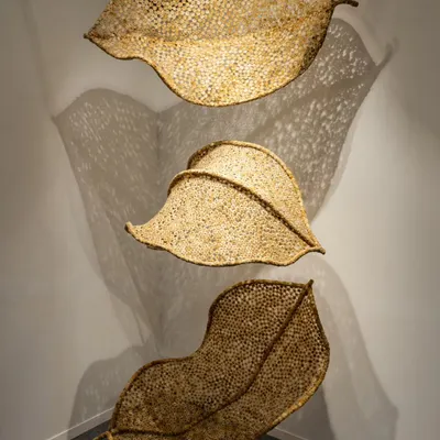 The 'Biography' series installed for an exhibition, where the three leaf-like forms create a dynamic interplay of light and shadow. Each sculpture is suspended to appear weightless, embodying the idea of a memory floating in space.