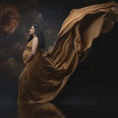 The golden glow of motherhood. The rich, warm tones of this maternity gown reflect the nurturing energy of this journey, with the dramatic sweep of fabric giving the impression of life in motion.
