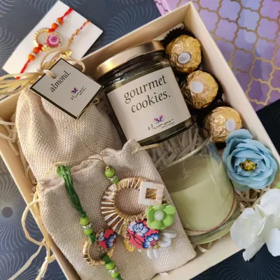 A gorgeous Rakhi hamper filled with treats to celebrate the bond of siblings. This box includes a designer lumba rakhi set, a jar of gourmet cookies, Ferrero Rocher chocolates, and a scented candle.