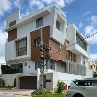 A contemporary residence for Mr. Satish, defined by its interlocking blocks, cantilevered structures, and a mix of wood-paneled and white stucco surfaces.