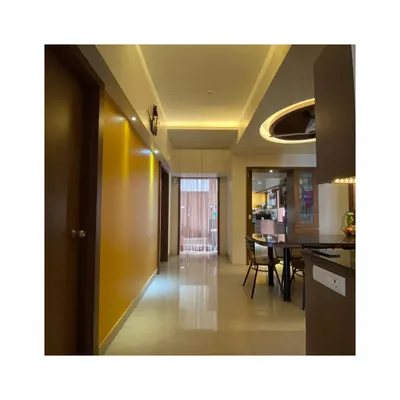 In the Malhotra Apartment, we used a warm and neutral palette for the common areas. This hallway features a mustard accent wall that leads the eye towards the dining area, demonstrating our use of color to define spaces.